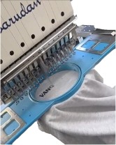Multi-needle embroidery machine stitching a garment